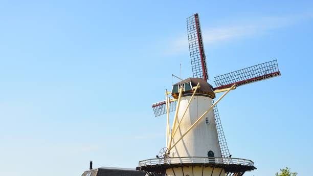 istock Classical Dutch landscape with a white windmill on a field against blue sky 1059155810