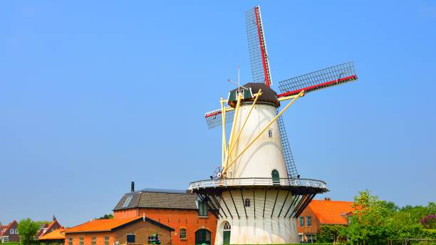 istock Classical Dutch landscape with a white windmill on a field against blue sky 1059155812