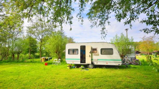 istock Caravan trailer camping on a green lawn under a tree in springtime 1059155820