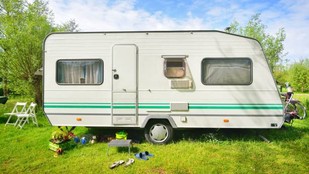 istock Caravan trailer camping on a green lawn under a tree in springtime 1059155824