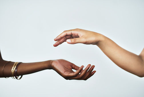 Cropped studio shot of two women touching hands against a gray background