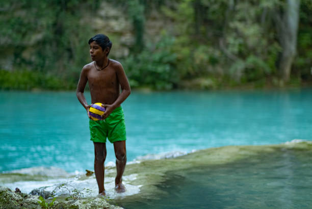 Latin boy having fun getting a bath in the middle of October on a turquoise water river. Global warming affects water temperature. SentierElsa, Colle Val d'Elsa. Tuscany Italy Europe