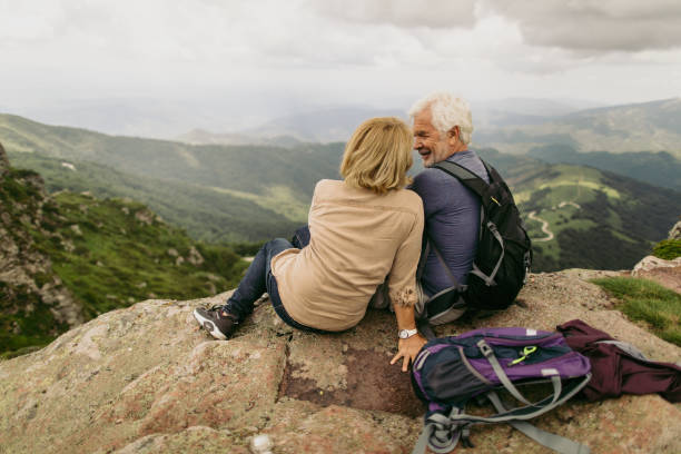 Together on the top Photo of an elderly couple during their hike with backpacks, reached the top of the mountain clambering photos stock pictures, royalty-free photos & images