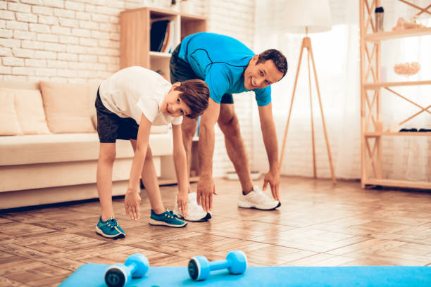 istock Man and Boy in Sport Uniform Doing Warm Up at Home 1059162010
