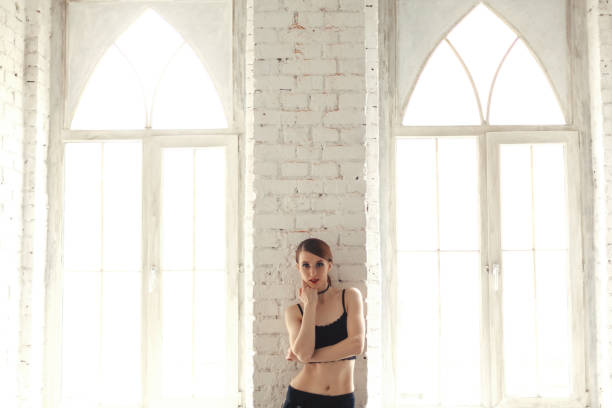 istock Attractive redhead model woman standing and posing near window 1059162748