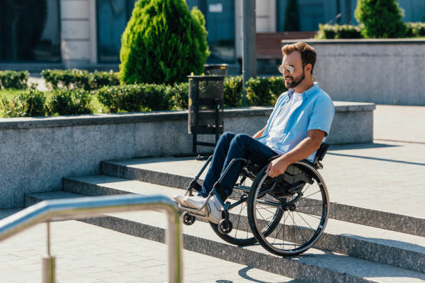 istock handsome man in sunglasses using wheelchair on stairs without ramp 1059163358