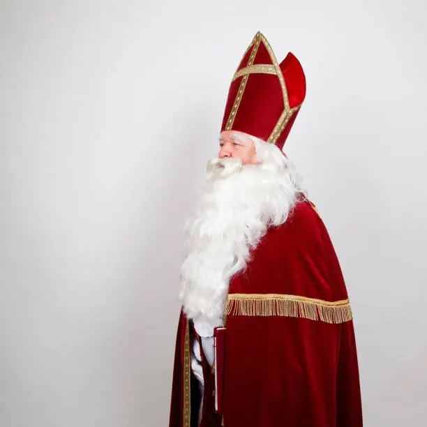 Saint Nicholas with his red costume on white looking at the left side