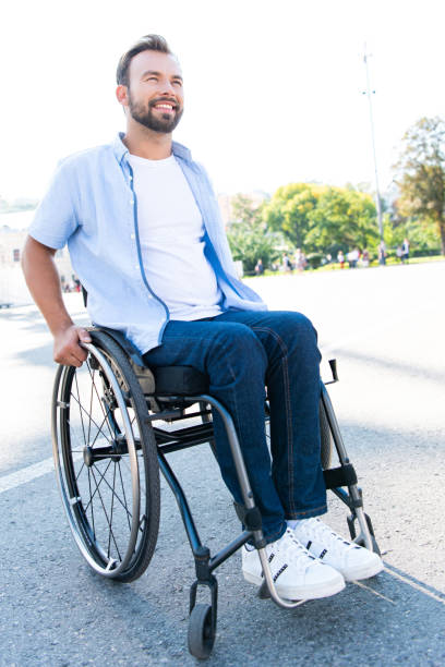 istock handsome smiling man using wheelchair on street and looking up 1059170768