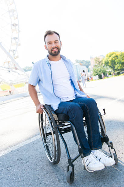 istock smiling handsome man using wheelchair on street and looking at camera 1059170800