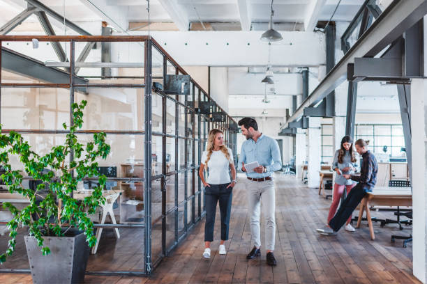 istock smiling young business colleagues using digital tablet and talking while walking at workspace 1059172598