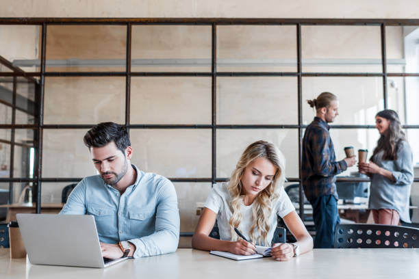 istock young business people working at workplace while colleagues drinking coffee behind 1059172618
