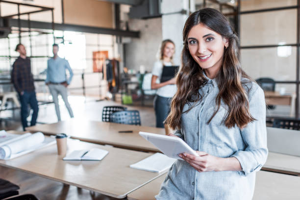 istock beautiful young businesswoman using digital tablet and smiling at camera in office 1059172650