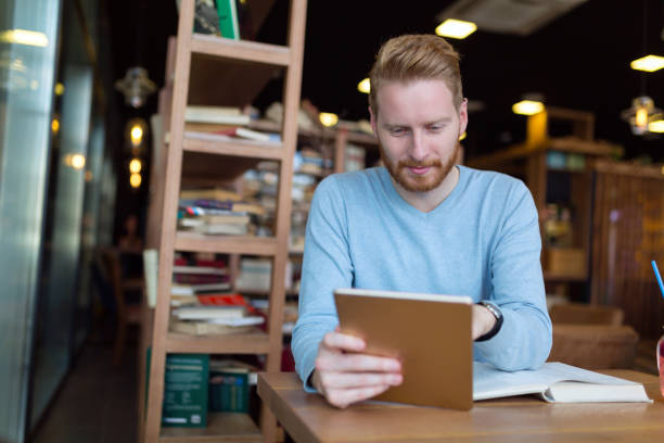 istock Young man using digital tablet in coffee shop 1059177398