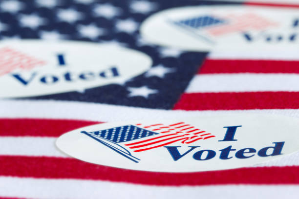 I Voted 'I Voted' stickers on the US flag background. voter id stock pictures, royalty-free photos & images