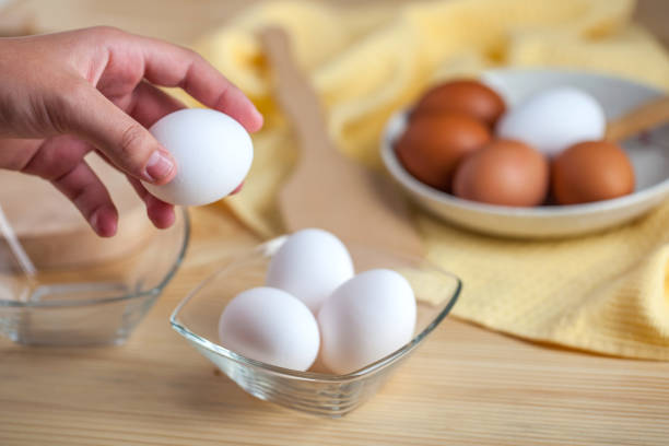 istock Woman hands breaking an egg, eggs at the background 1059180912