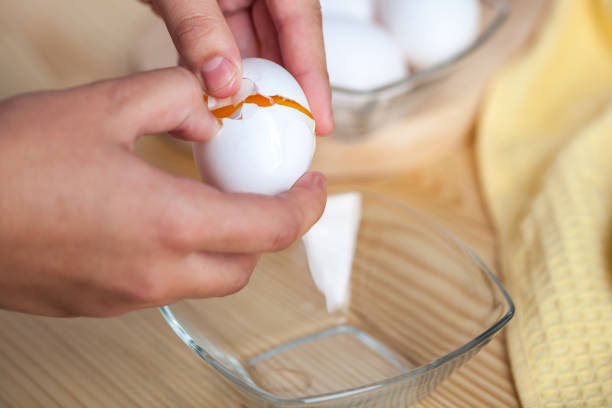 istock Woman hands breaking an egg to separate egg white and yolks, egg shells at the background 1059180922