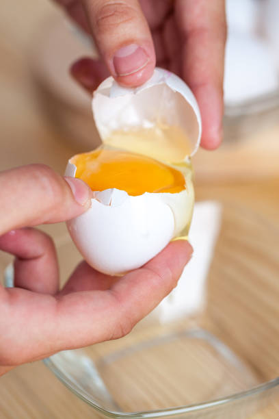 istock Woman hands breaking an egg to separate egg white and yolks, egg shells at the background 1059180930