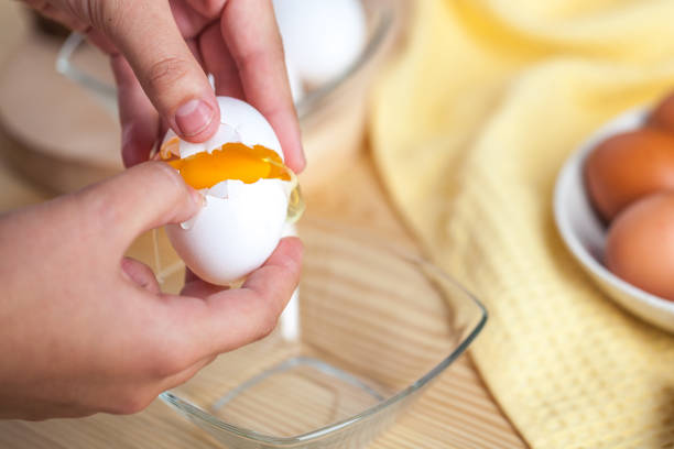 istock Woman hands breaking an egg to separate egg white and yolks, egg shells at the background 1059180944