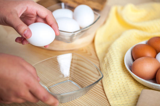 istock Woman hands breaking an egg to separate egg white and yolks, egg shells at the background 1059180952