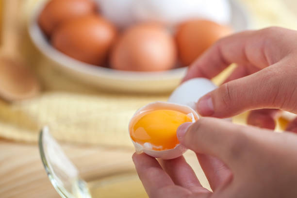 istock Woman hands breaking an egg to separate egg white and yolks, egg shells at the background 1059180958