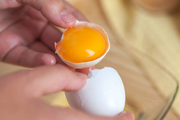 istock Woman hands breaking an egg to separate egg white and yolks, egg shells at the background 1059180960