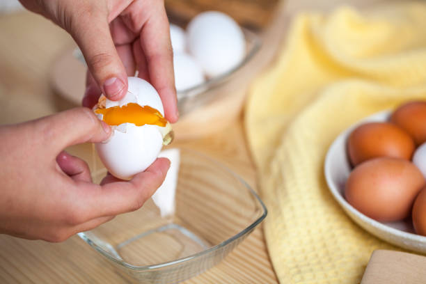 istock Woman hands breaking an egg to separate egg white and yolks, egg shells at the background 1059180980