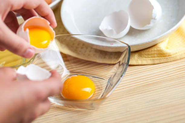 istock Woman hands breaking an egg to separate egg white and yolks, egg shells at the background 1059181018