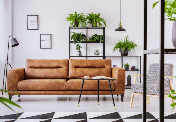 istock Patterned armchair next to brown leather couch in white living room interior in modern apartment 1059181570