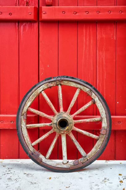 Antique vintage wooden wheel reclined to a red wooden door