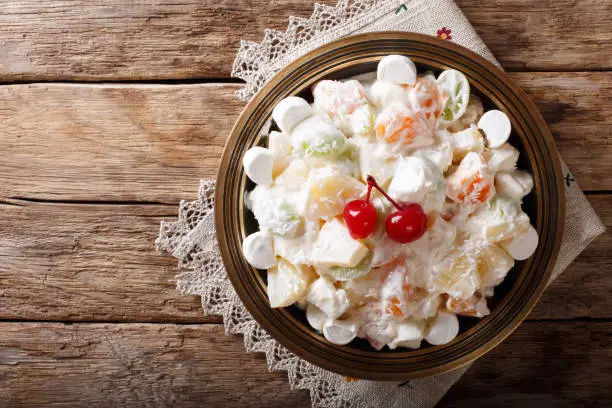 Photo of fruit salad Ambrosia from pineapple, tangerine, grapes and marshmelow close-up. horizontal top view