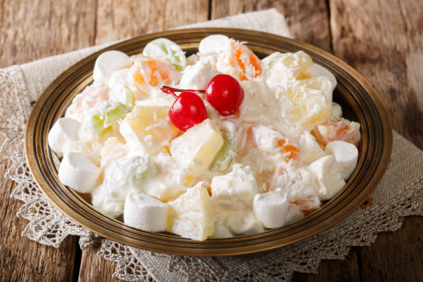 fruit salad from pineapple, oranges, grapes and coconut with marshmallow and vanilla yogurt close-up. horizontal fruit salad from pineapple, oranges, grapes and coconut with marshmallow and vanilla yogurt close-up on a plate. horizontal ragweed stock pictures, royalty-free photos & images