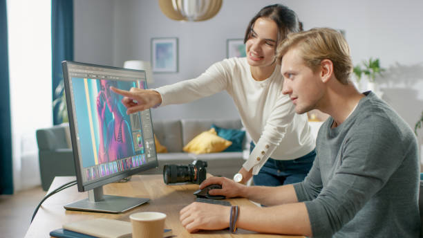 Male and Female Professional Editors Talk while Working in Photo Editing App / Software on a Personal Computer. Photo Editors Retouching Photos of a Beautiful Girl. Mock-up Software Design. Female Points at the Screen.