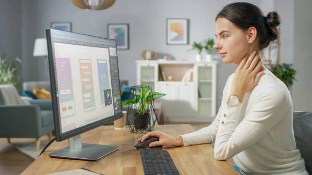 istock Beautiful Female Software Designer Works on a UX / UI Mobile App Template, Uses Personal Computer. Freelance Programmer Working from Home. Mock-up App Design. 1059208542