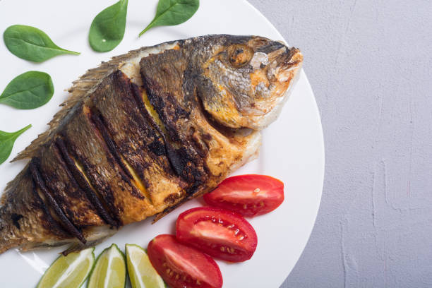 istock Fried fish dorado with lime , tomatoes and spinach 1059208560