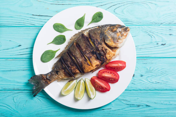 istock Fried fish dorado with lime , tomatoes and spinach 1059208594