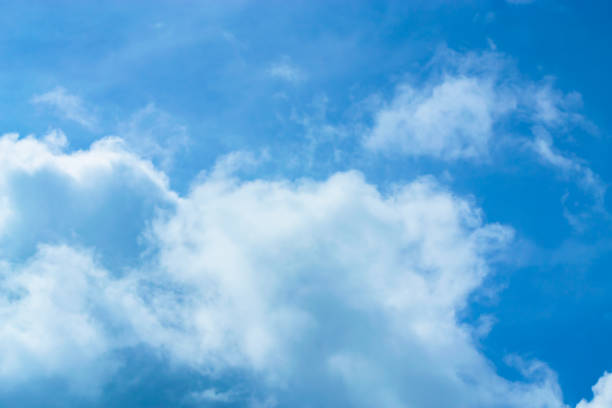 istock Blue background with small clouds floating across the sky. 1059209512