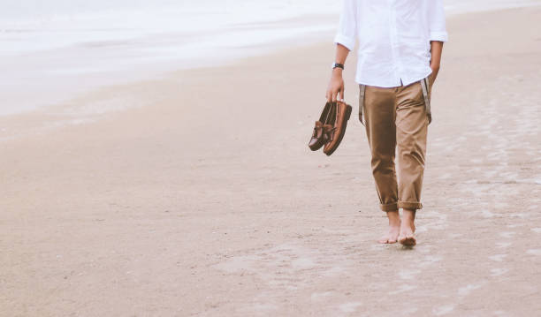 istock Alone man walking on the beach carrying leather shoes 1059214016