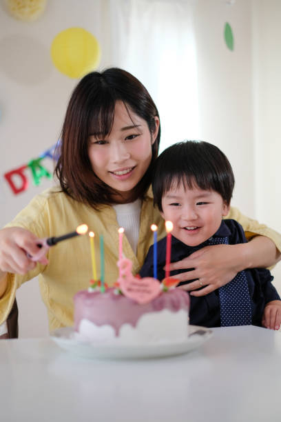 istock Mother lighting candles on her son's birthday cake 1059216930