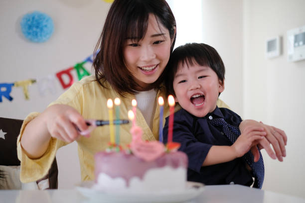 istock Mother lighting candles on her son's birthday cake 1059216960