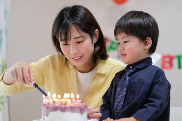 istock Mother lighting candles on her son's birthday cake 1059218430