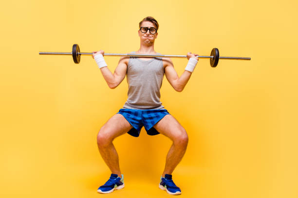 Full length body size of funky caucasian guy in glasses, doing physical exercises with dumbbell, isolated over bright vivid yellow background Full length body size of funky caucasian guy in glasses, doing physical exercises with dumbbell, isolated over bright vivid yellow background weakness stock pictures, royalty-free photos & images