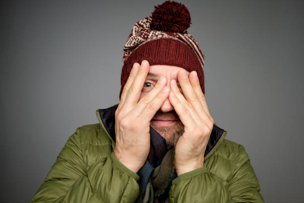 Handsome mature man covering eyes with hands while standing grey background in warm winter clothes See nothing concept. Handsome mature man covering eyes with hands while standing grey background in warm winter clothes hair covering eyes stock pictures, royalty-free photos & images