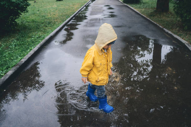 istock Little boy walking outdoors and jumping on puddle 1059247580