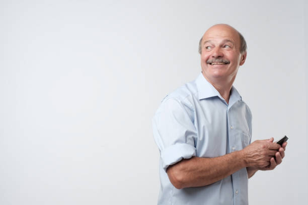 istock Mature businessman with mustache in blue shirt using phone to write sms. 1059249126