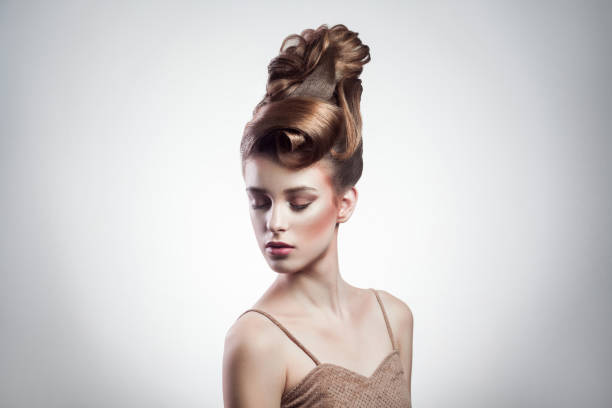 portrait of attractive brunette woman with stylish hairdo and makeup posing with closed eyes on isolated grey background. indoor, studio shot on copy space.