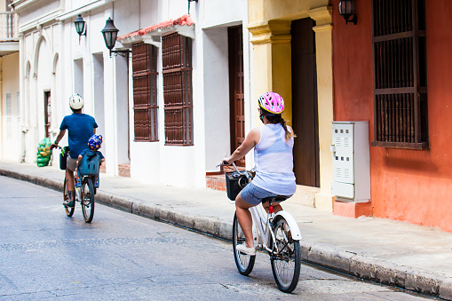 CARTAGENA DE INDIAS, COLOMBIA - AUGUST, 2018: Family riding on rental bikes around the walled city in Cartagena de Indias