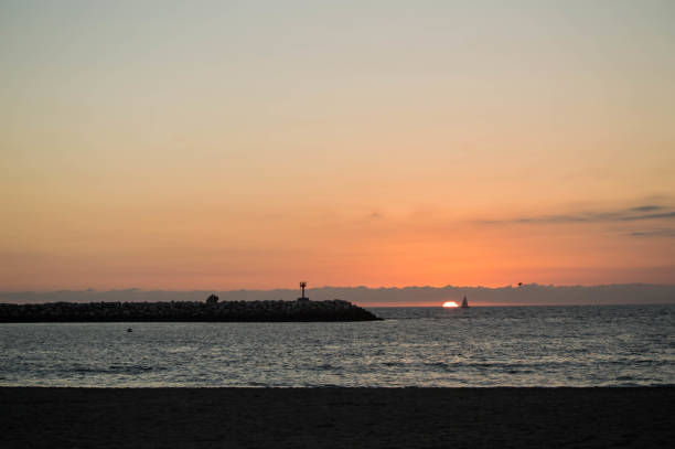 Sunset over Marina del Rey Peninsula in Los Angeles, CA with sailboat and birds