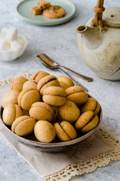 istock Baci di dama': delicious chocolate cookies with hazelnuts and topping on delicate background 1059262152