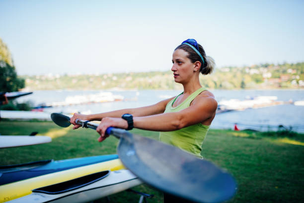 Portrait of active sport woman - She is professional kayaker and practicing on river in summer sunset. Muscular woman rowing and kayaking.