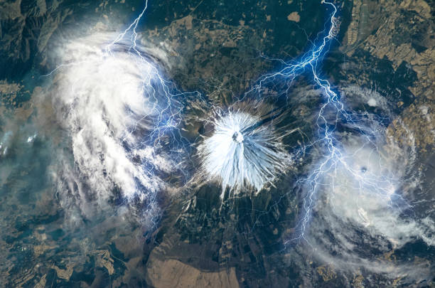 Mt. Fuji, Japan. Snow-capped Fuji Volcano surrounded by two hurricane clouds and huge lightening bolts, collage. Satellite view. Elements of this image furnished by NASA. Mt. Fuji, Japan. Snow-capped Fuji Volcano surrounded by two hurricane clouds and huge lightening bolts, collage. Satellite view. Elements of this image furnished by NASA. typhoon photos stock pictures, royalty-free photos & images